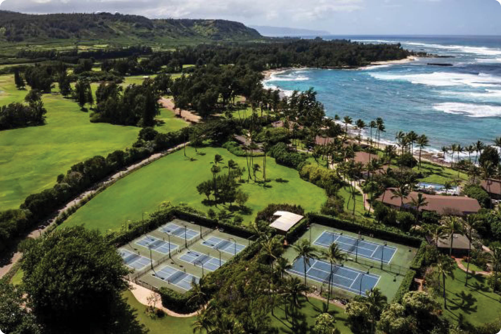 A tennis court with a green surface is located next to a beach. AI generated content