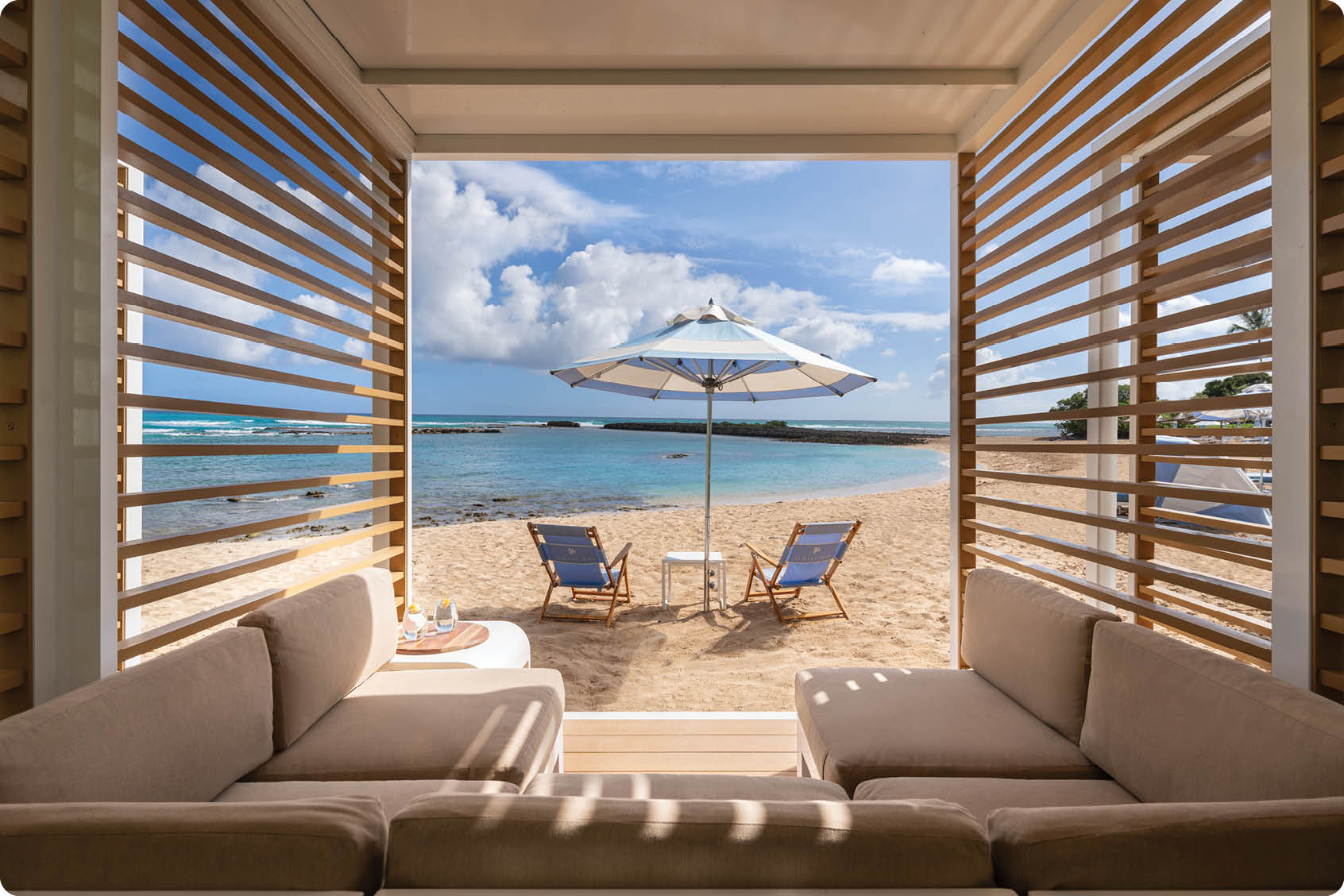 A couch with two chairs in front of a window overlooking a beach. AI generated content