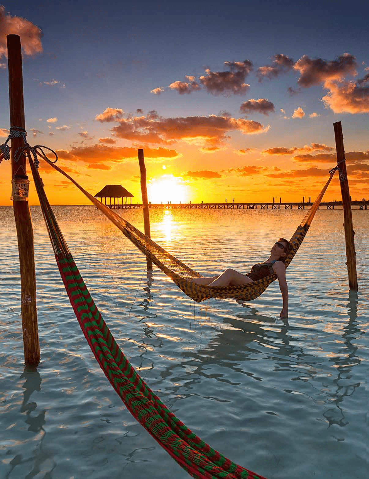 A woman is lying on a hammock in the ocean, enjoying the sunset. AI generated content